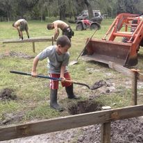 a boy helping dig hole to build a barn