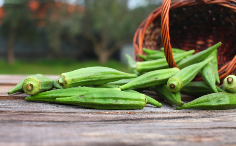 basket-of-okra-pods-spilled-on-wooden-table-outside