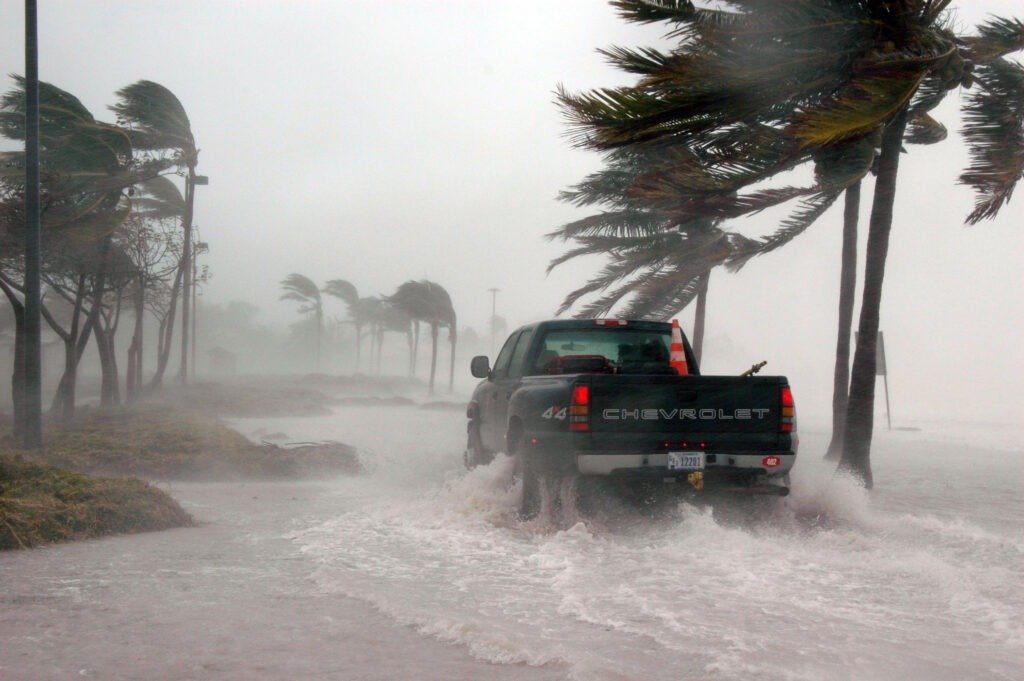 a truck driving through a flooded road during a hurricane