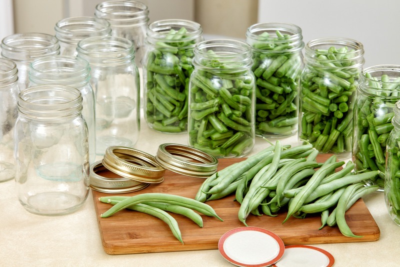 canning jars of green beans with fresh beans on cutting board