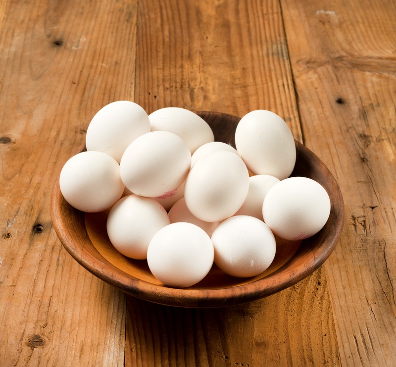 White eggs in a bowl and wooden background