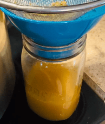 straining bone broth into the jars