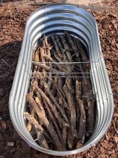 fill the bottom of the raised bed with sticks and logs to save space